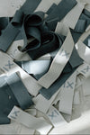 Scattered black and white tonal resistance bands in light and heavy set with 'X' barre belle logo on a light gray surface